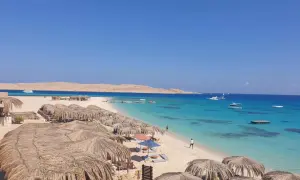 Rajska plaża z palmowymi parasolami i turkusową wodą. Idealne miejsce na relaks i odkrywanie atrakcji Marsa Alam.