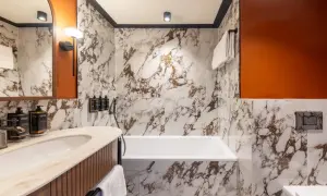 Łazienka w Mercure Gdynia Centrum. Marmurowe ściany, wanna, umywalka i pomarańczowe akcenty. Opinie o hotelu często podkreślają jego nowoczesny design.