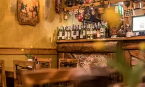 Wnętrze karczmy z butelkami alkoholu na półce. W tle obrazek z epoki. Opinie o "niebo w gębie" Karpacz mogą być pozytywne.