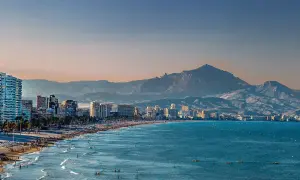 Alicante w grudniu: słoneczna plaża pełna ludzi, turkusowe morze i góry w tle. Idealna pogoda na spacer.