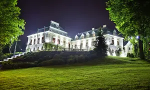 Elegancki pałac nocą, oświetlony blaskiem lamp, otoczony zielenią. Idealne miejsce na romantyczny wypad, jak w najlepszych hotelach dla dorosłych.