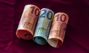 Dwa banknoty 10 euro i jeden 20 euro leżą na bordowym materiale. Łotwa waluta euro.
