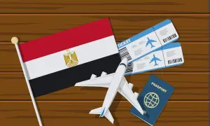 Flaga Egiptu, dwa bilety lotnicze, paszport i samolot. Zastanawiasz się, ile kosztuje wiza do Egiptu?