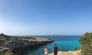 Para spaceruje po klifie, podziwiając turkusowe wody i skaliste wybrzeże Akamas.