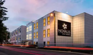 Novalis Hotel Dresden, z oświetlonymi oknami i neonowym znakiem, pokazuje, czym się różni hotel od motelu: oferuje więcej niż tylko nocleg.