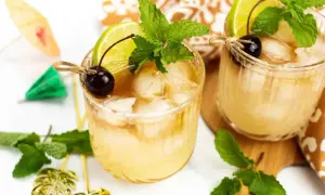 Dwa orzeźwiające drinki Mai Tai z lodem, limonką, wiśnią i miętą, ozdobione parasolkami.