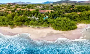 Rajskie wakacje na Kostaryce: piaszczysta plaża, palmy, basen i turkusowe fale oceanu. Idealne miejsce na relaks.