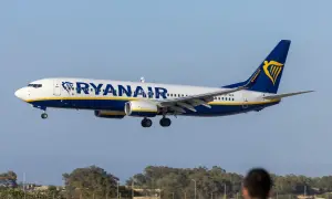 Samolot Ryanair zbliża się do lądowania. Widok z lotniska, gdzie czeka pasażer na odprawę.