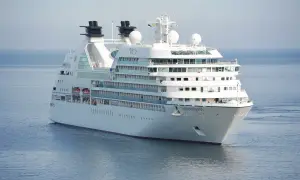 Biały statek wycieczkowy Seabourn Quest płynie po spokojnym, błękitnym morzu.