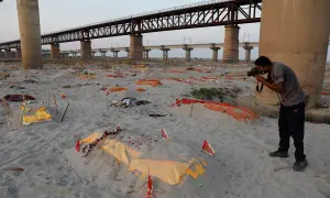 Brzeg rzeki Ganges, gdzie leżą przykryte materiałem ciała, tworzy widok przypominający cmentarzysko. Fotograf dokumentuje tę smutną rzeczywistość.