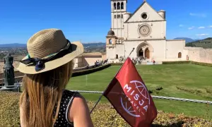 Kobieta w kapeluszu z flagą Misja Travel przed bazyliką. Wspaniałe widoki i pozytywne misja travel opinie.