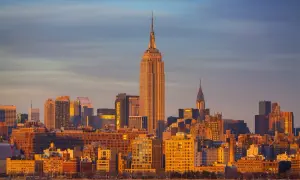 Zachód słońca nad Manhattanem. Widać Empire State Building i Chrysler Building. Zastanawiasz się, ile się leci do Nowego Jorku?