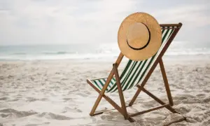 Pusta leżanka z kapeluszem na plaży, idealna na węgry wakacje. Słońce odbija się w wodzie, zapraszając do relaksu.