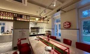 Wnętrze restauracji z długim stołem, czerwonymi krzesłami i piecem do pizzy. Otto Pompieri opinie pozytywne, warto odwiedzić!