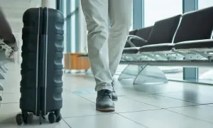 Mężczyzna z walizką na lotnisku, w drodze na wakacje. Pozytywne rego-bis opinie potwierdzają komfort podróży.