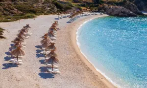 Rządki parasoli i leżaków na kamienistej plaży, obok krystalicznie czystej, turkusowej wody. Jedna z najpiękniejszych plaż w Europie.