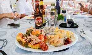 Malta jedzenie: talerz z tuńczykiem, kaparami, fasolą i pastą. Obok piwo i okulary przeciwsłoneczne.