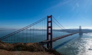 Ikoniczny most w San Francisco rozciąga się nad błękitną wodą, z panoramą miasta w oddali.
