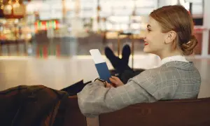 Kobieta z paszportem w ręku czeka na lot. Czy do Dubaju trzeba paszport? Tak, jest niezbędny do podróży.