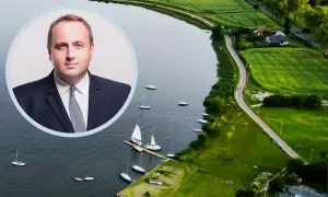 Portret mężczyzny w garniturze na tle malowniczego zalewu zemborzyckiego z żaglówkami.