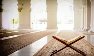 Otwarta księga na drewnianym stojaku w meczecie, symbolizująca turcja religia. Wnętrze z łukami i dywanami tworzy atmosferę spokoju.