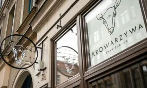 Neonowy znak i logo na szybie lokalu Krowarzywa. Wesoła krowa zaprasza na wegańskie burgery.