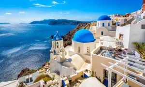 Białe domy z niebieskimi kopułami na greckich wyspach, Santorini, z widokiem na turkusowe morze.