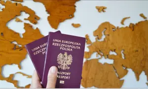 Dwa polskie paszporty, w tym paszport tymczasowy dla dziecka, na tle drewnianej mapy Europy.