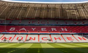 Puste trybuny Allianz Arena z napisem "BAYERN MÜNCHEN" w czerwonych i białych siedzeniach.