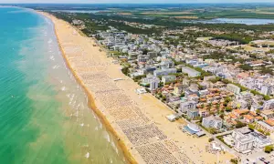 Słoneczna bibione plaża tętni życiem. Tysiące leżaków i parasoli tworzą barwny dywan, a turkusowe morze zaprasza do kąpieli.