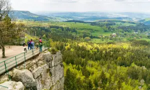 Widok na zielone wzgórza i lasy z platformy widokowej. W oddali widać zabudowania. To piękna kotlina kłodzka.