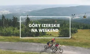 Góry Izerskie Polska: rowerzyści pędzą po górskiej drodze, w tle kolejka gondolowa i rozległy krajobraz.