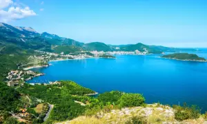 Widok na zatokę i miasteczko na wybrzeżu, otoczone zielonymi wzgórzami. To piękna riwiera olimpijska.