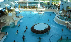 Wesoła atmosfera w aquaparku w Sopocie. Ludzie kąpią się w basenach, relaksują w jacuzzi. Wiele pozytywnych **aquapark sopot opinie** potwierdza, że to świetne miejsce na rodzinny wypoczynek.