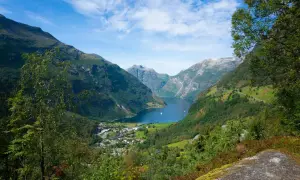 Widok na malownicze **Stavanger fiordy** z zielonymi zboczami gór, błękitną wodą i małym miasteczkiem u podnóża.