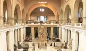 Wielka sala w muzeum w Kairze, pełna starożytnych posągów i artefaktów. Monumentalne rzeźby faraonów dominują w centrum.