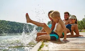 Rodzina pluska się w jeziorze, tworząc fontanny wody. To fajne miejsce na wakacje z dzieckiem w Polsce.