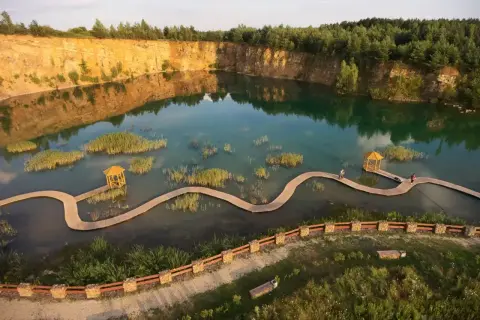Malowniczy zalew w kamieniołomie Gródek Jaworzno, z drewnianymi kładkami i altanką. Warto sprawdzić park Gródek Jaworzno cena wstępu.