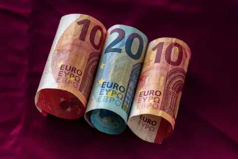 Dwa banknoty 10 euro i jeden 20 euro leżą na bordowym materiale. Łotwa waluta euro.