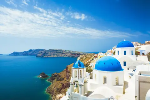 Santorini: białe domy, niebieskie kopuły kościołów i turkusowe morze. Idealne miejsce na tanie wakacje w Grecji.