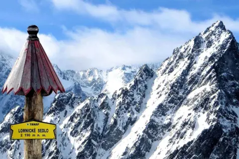 Słowacja góry: szczyt Łomnickie Sedlo (2190 m n.p.m.) w Tatrach Wysokich, pokryty śniegiem, z charakterystycznym drewnianym słupkiem i tabliczką.