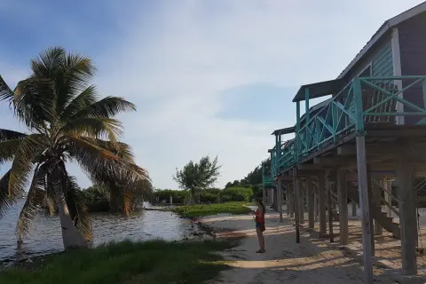Kobieta na plaży, palmy i domki na palach. Idealne miejsce na belize wakacje.