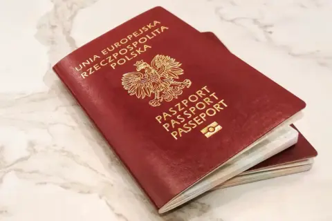 Dwa polskie paszporty, symbole wolności podróżowania i jedne z najsilniejszych paszportów na świecie, leżą na marmurowym blacie.