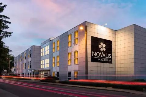 Novalis Hotel Dresden, z oświetlonymi oknami i neonowym znakiem, pokazuje, czym się różni hotel od motelu: oferuje więcej niż tylko nocleg.
