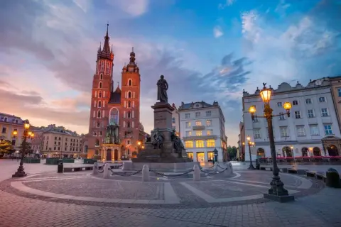 Zachód słońca nad Rynkiem Głównym. Bazylika Mariacka i pomnik Mickiewicza w pięknym, historycznym otoczeniu. Stare miasto w Krakowie zachwyca o każdej porze.