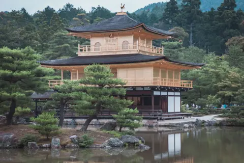 Złoty Pawilon Kinkaku-ji, cel mojej wycieczki do Japonii, odbija się w spokojnej tafli stawu.