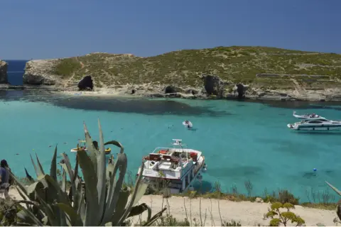 Malta wycieczki: turkusowa woda, łodzie i skaliste wybrzeże. Idealne miejsce na wakacje.