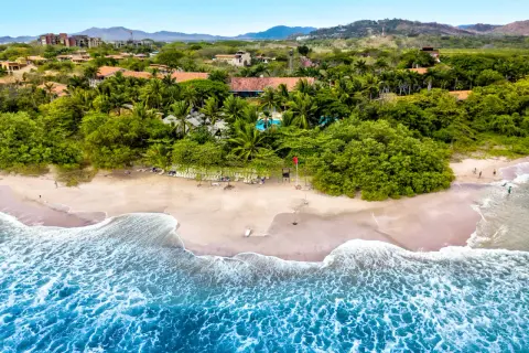 Rajskie wakacje na Kostaryce: piaszczysta plaża, palmy, basen i turkusowe fale oceanu. Idealne miejsce na relaks.