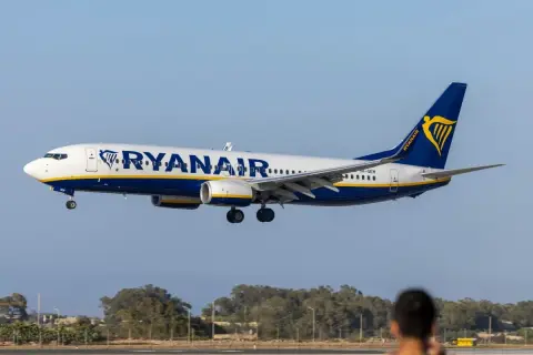 Samolot Ryanair zbliża się do lądowania. Widok z lotniska, gdzie czeka pasażer na odprawę.