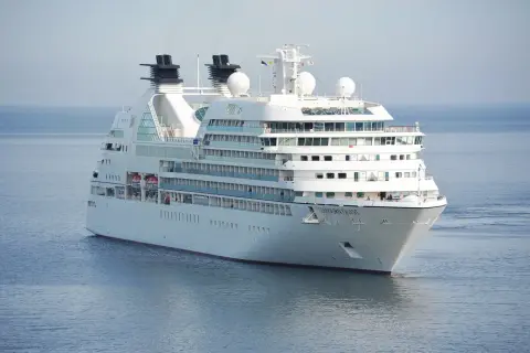 Biały statek wycieczkowy Seabourn Quest płynie po spokojnym, błękitnym morzu.